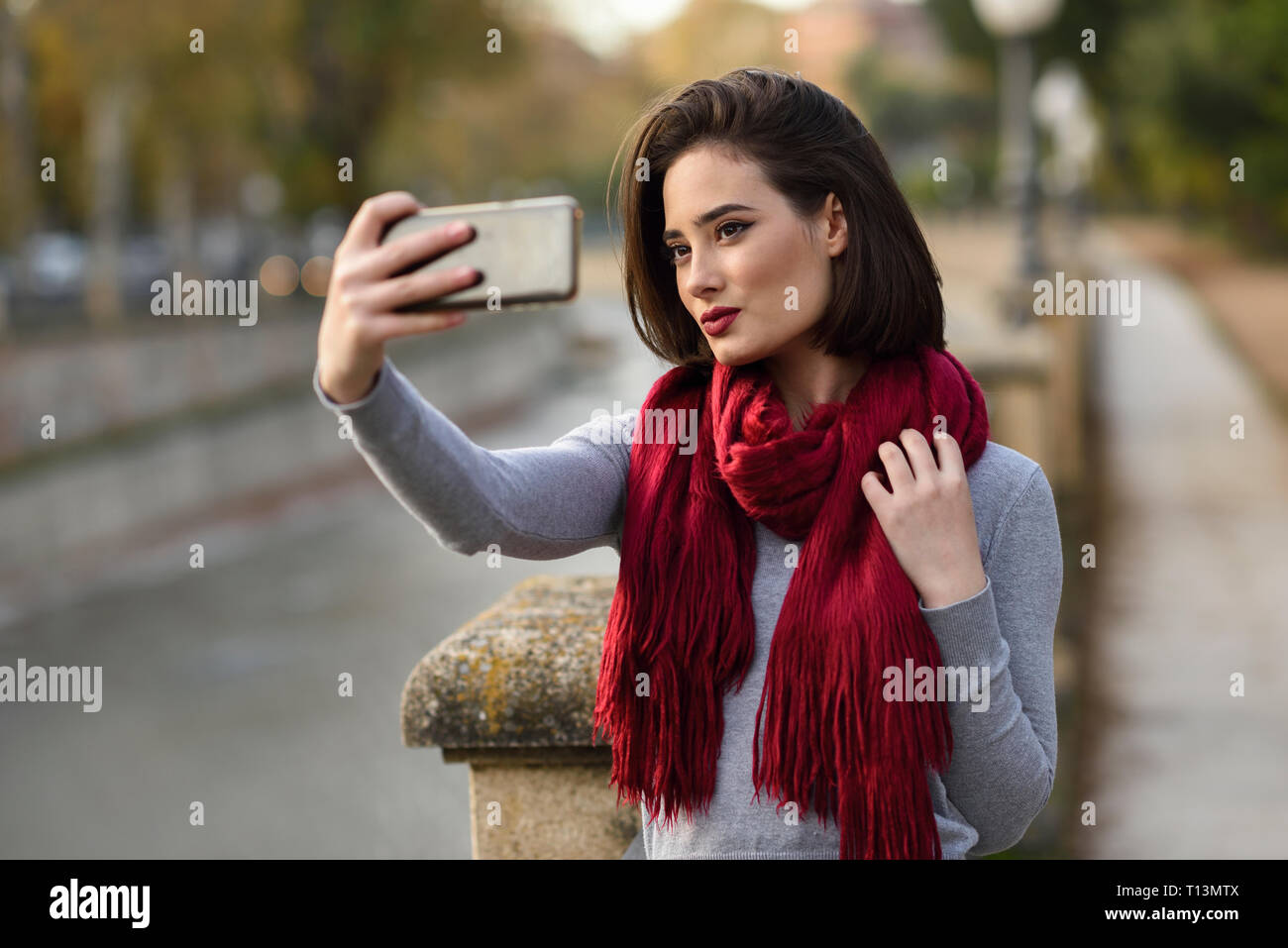Porträt der jungen Frau das Tragen der roten Schal unter selfie mit Handy Stockfoto