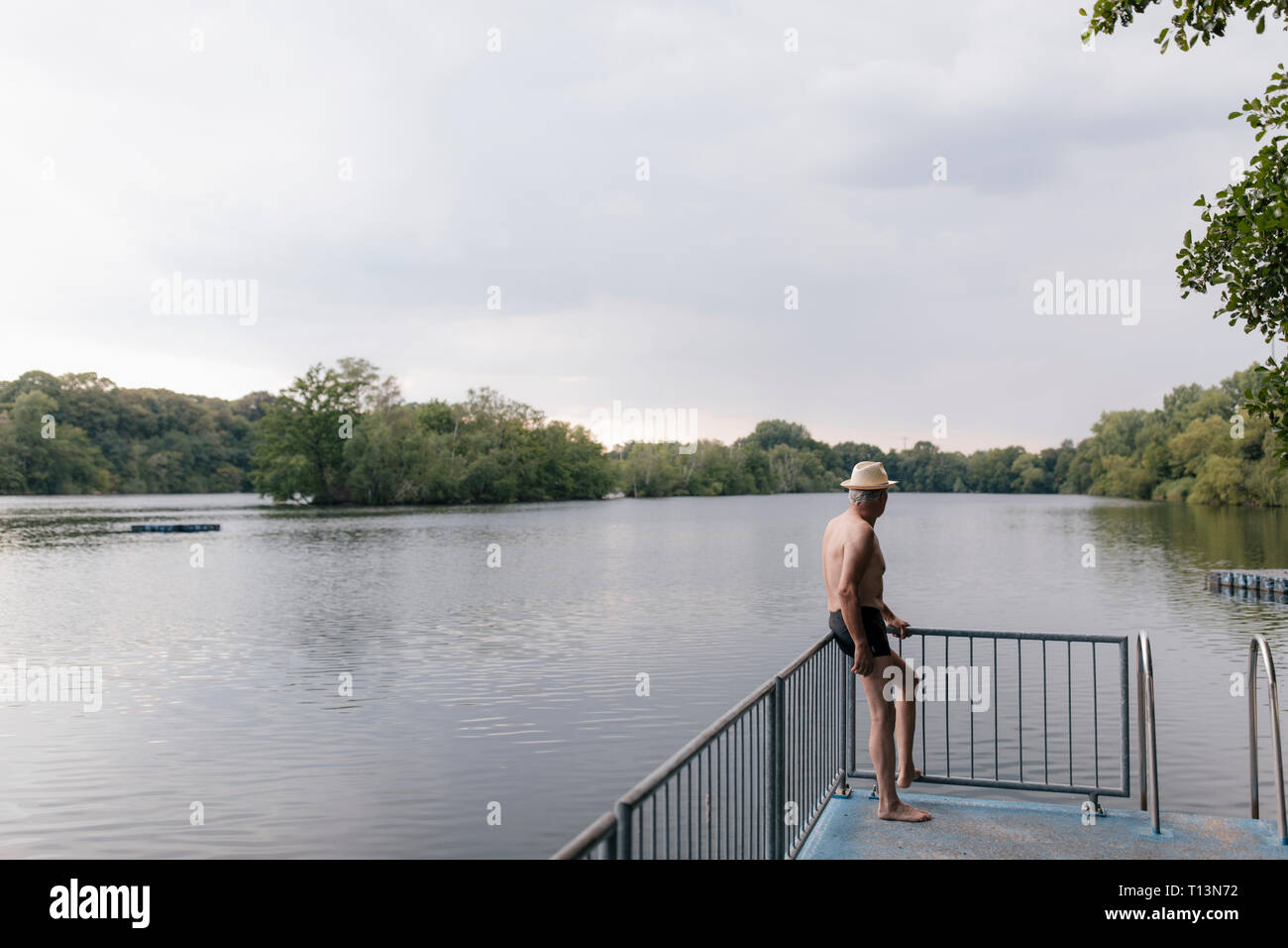 Älterer Mann mit Strohhut, der an einem See Stockfoto