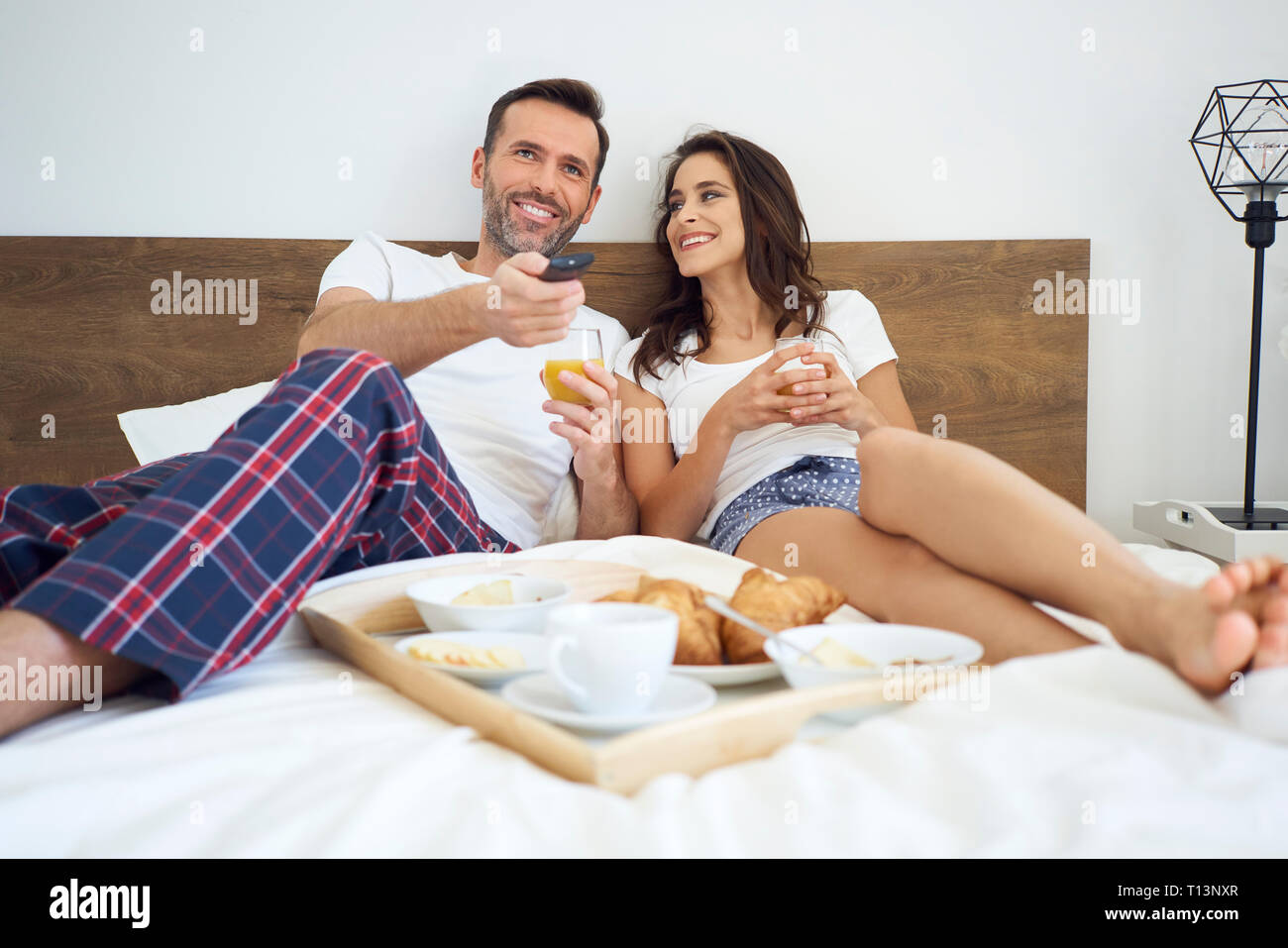 Glückliches Paar Frühstück im Bett, Fernsehen Stockfoto
