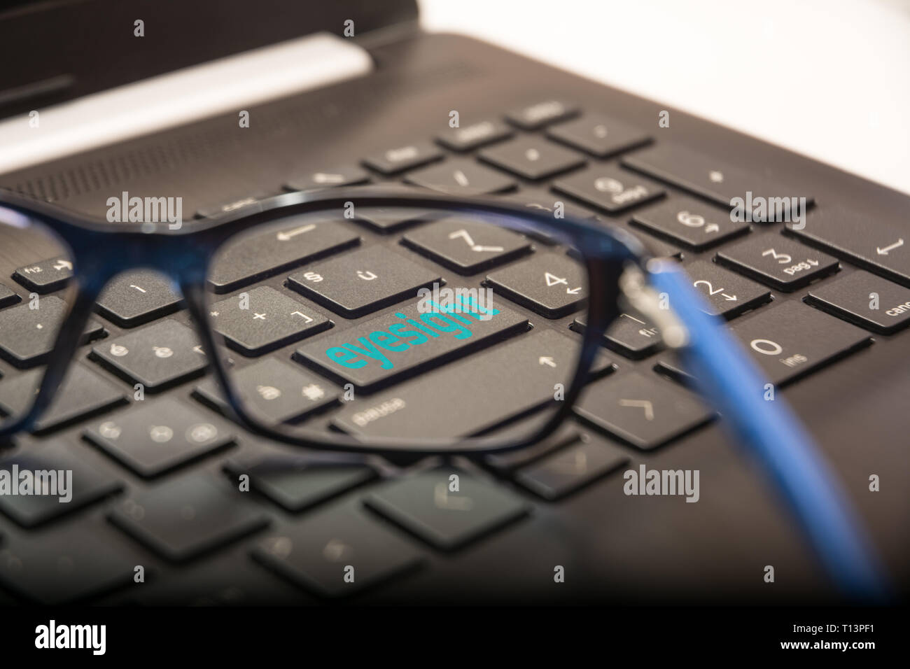Blick auf die PC-Tastatur durch die Linse der Gläser auf die Schaltfläche mit dem schriftlichen Sehvermögen Stockfoto