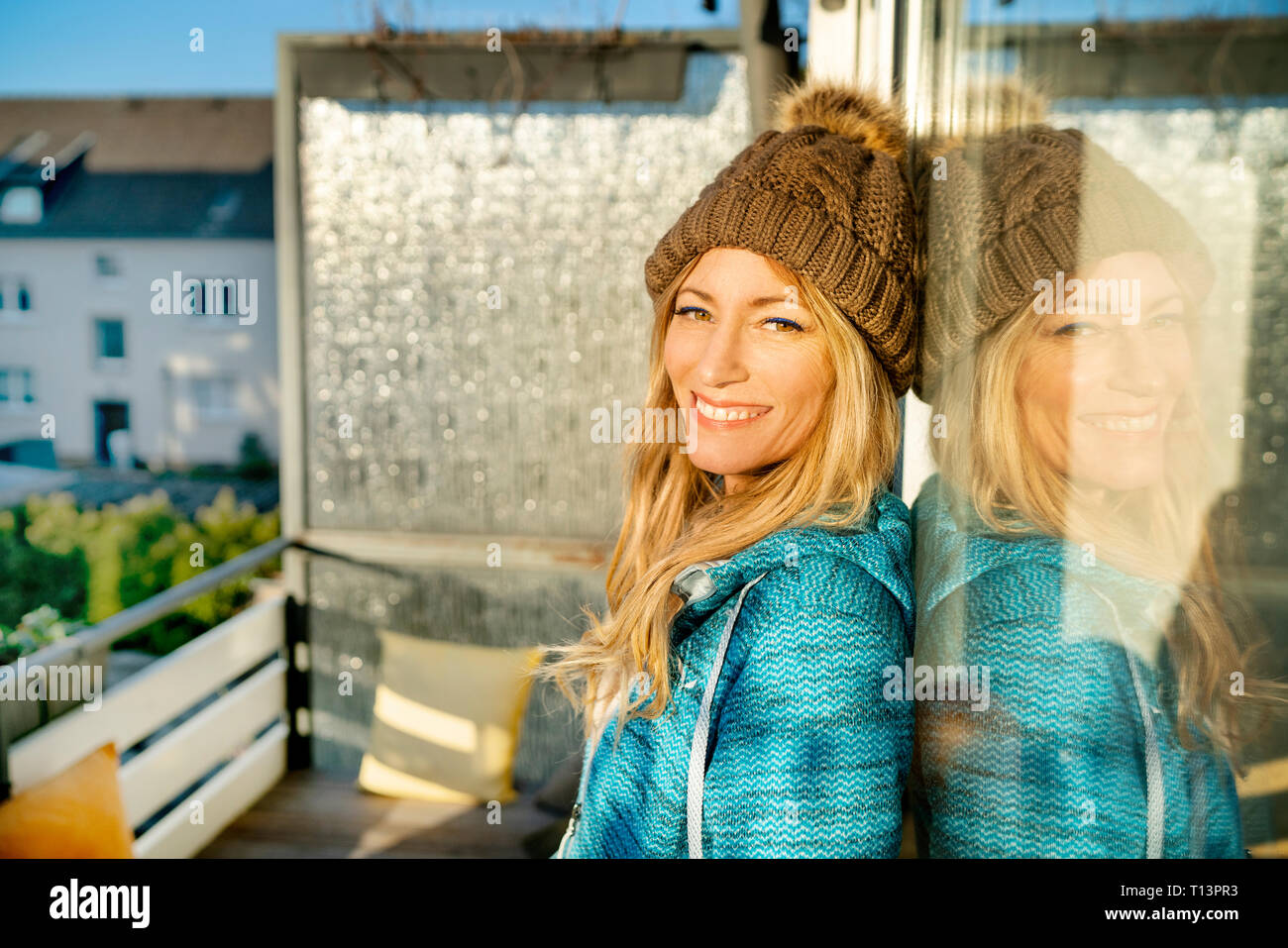 Portrait von lächelnden Blonde reife Frau tragen bobble Hut auf dem Balkon Stockfoto