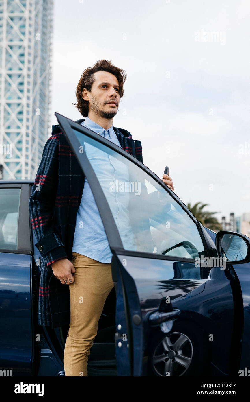Spanien, Barcelona, mann Aussteigen aus dem Auto mit Handy in der Hand Stockfoto