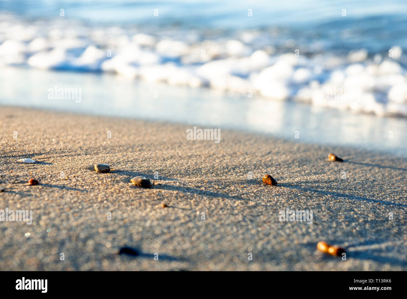 Kieselsteine am Sandstrand am Meer am Abend Stockfoto