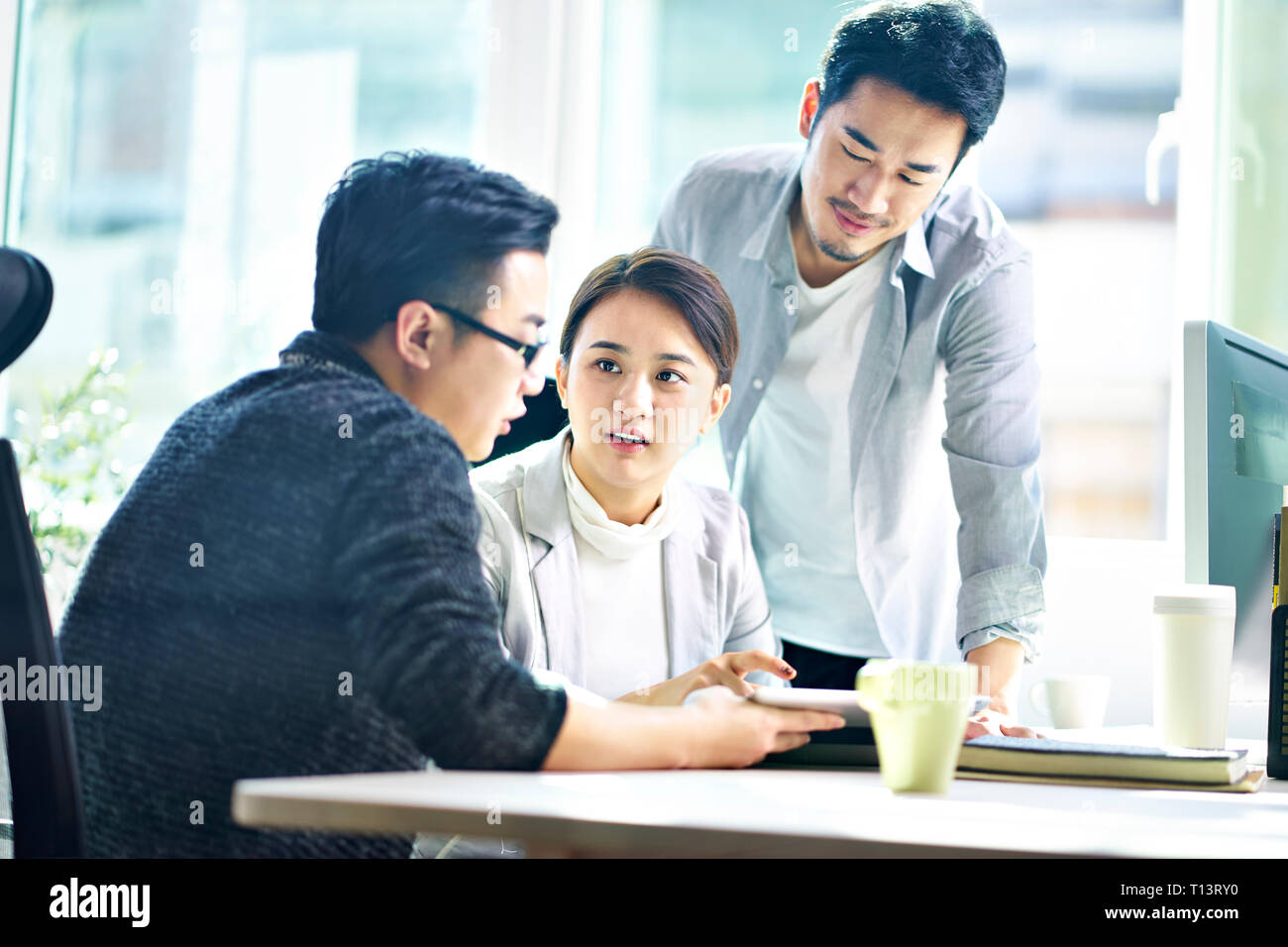 Drei jungen asiatischen Führungskräfte treffen im Büro diskutieren Geschäft mit digitalen Tablet. Stockfoto