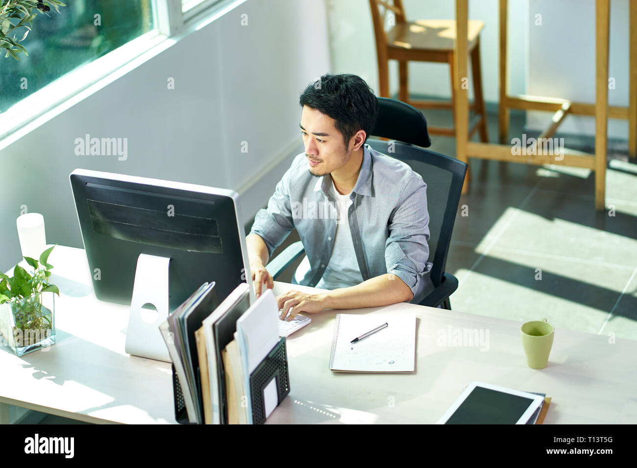 Hohe Betrachtungswinkel von jungen asiatischen Geschäft Person mit Desktop-PC im Büro Stockfoto