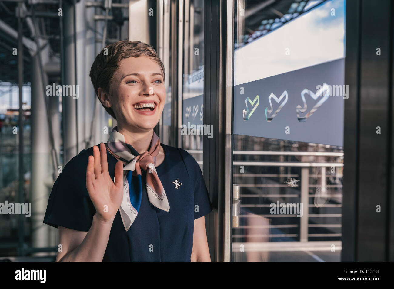 Happy airline Mitarbeiter winken aus dem Fenster auf das Airport Stockfoto