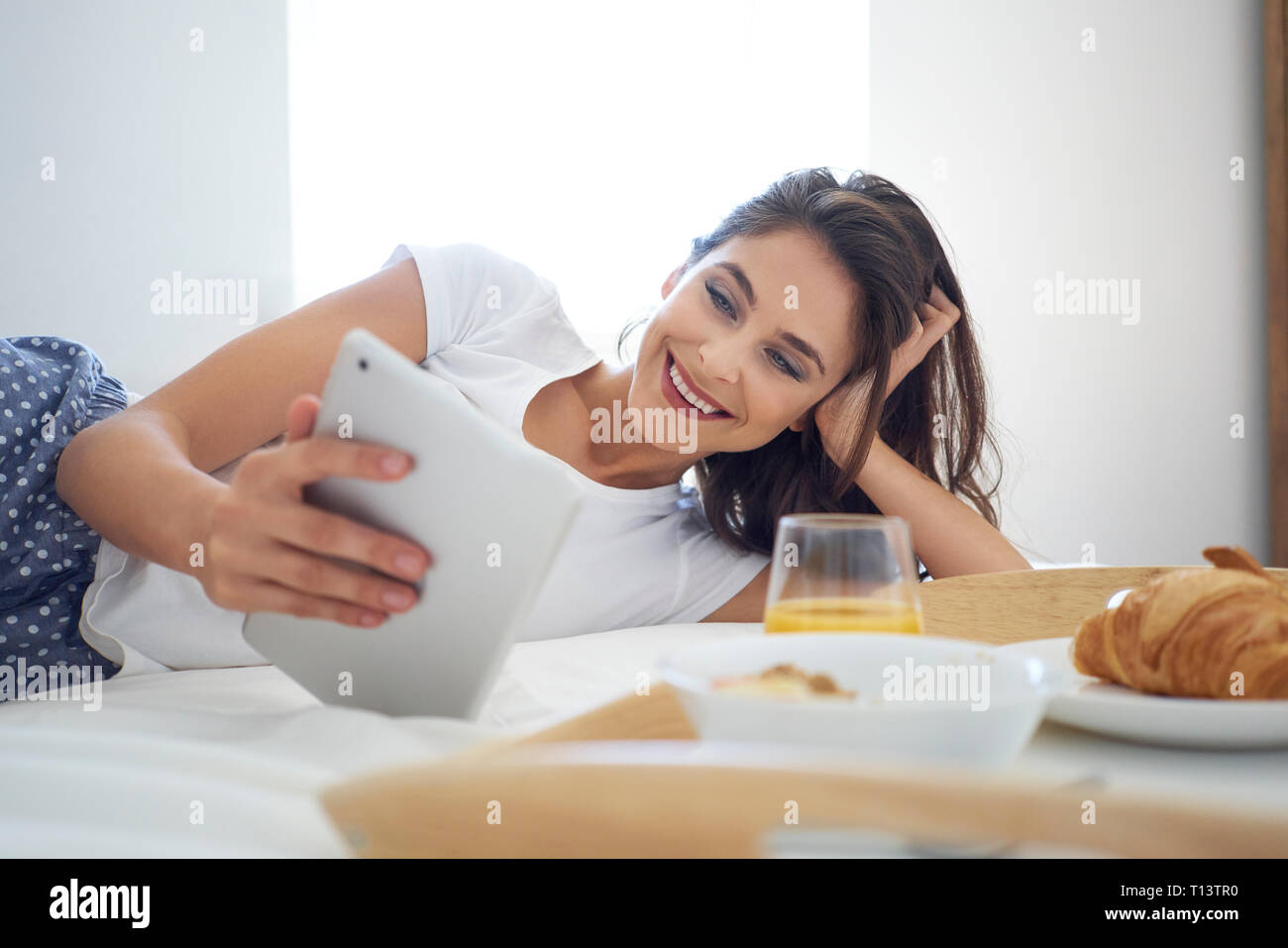 Junge Frau, Frühstück im Bett, mit digitalen Tablet, Lesen Stockfoto