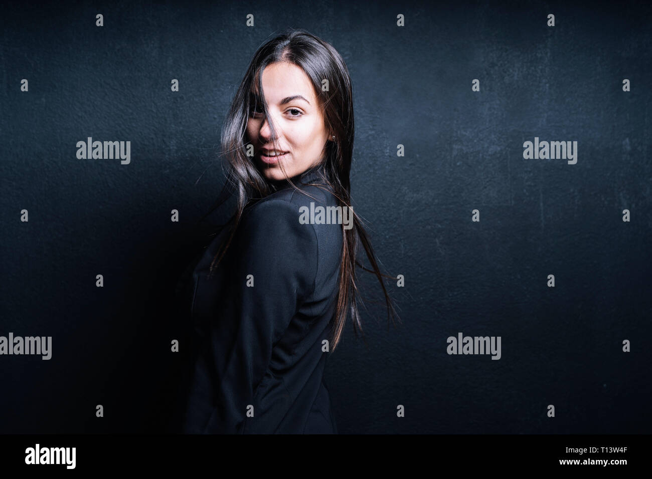 Porträt der jungen Frau mit schwarzen Blazer vor schwarzem Hintergrund Stockfoto