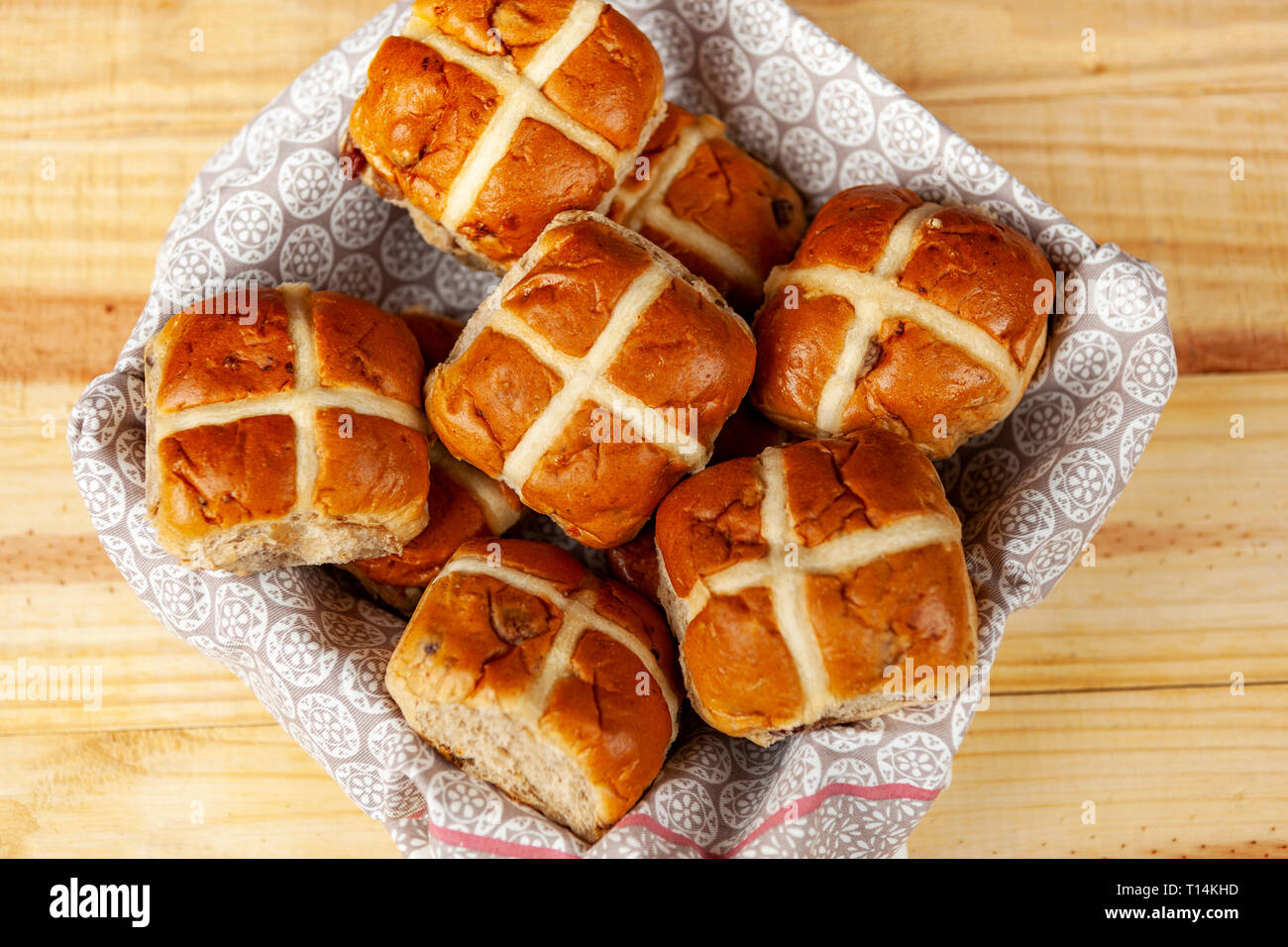 Frische Hot Cross Buns in ein Handtuch gesäumt Fach auf einer hölzernen Tischplatte Stockfoto