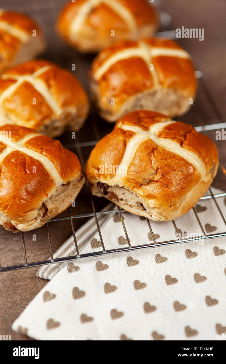 Frische Hot Cross Buns auf einem Gitter mit einer Serviette auf einem Stein Arbeitsplatte Stockfoto