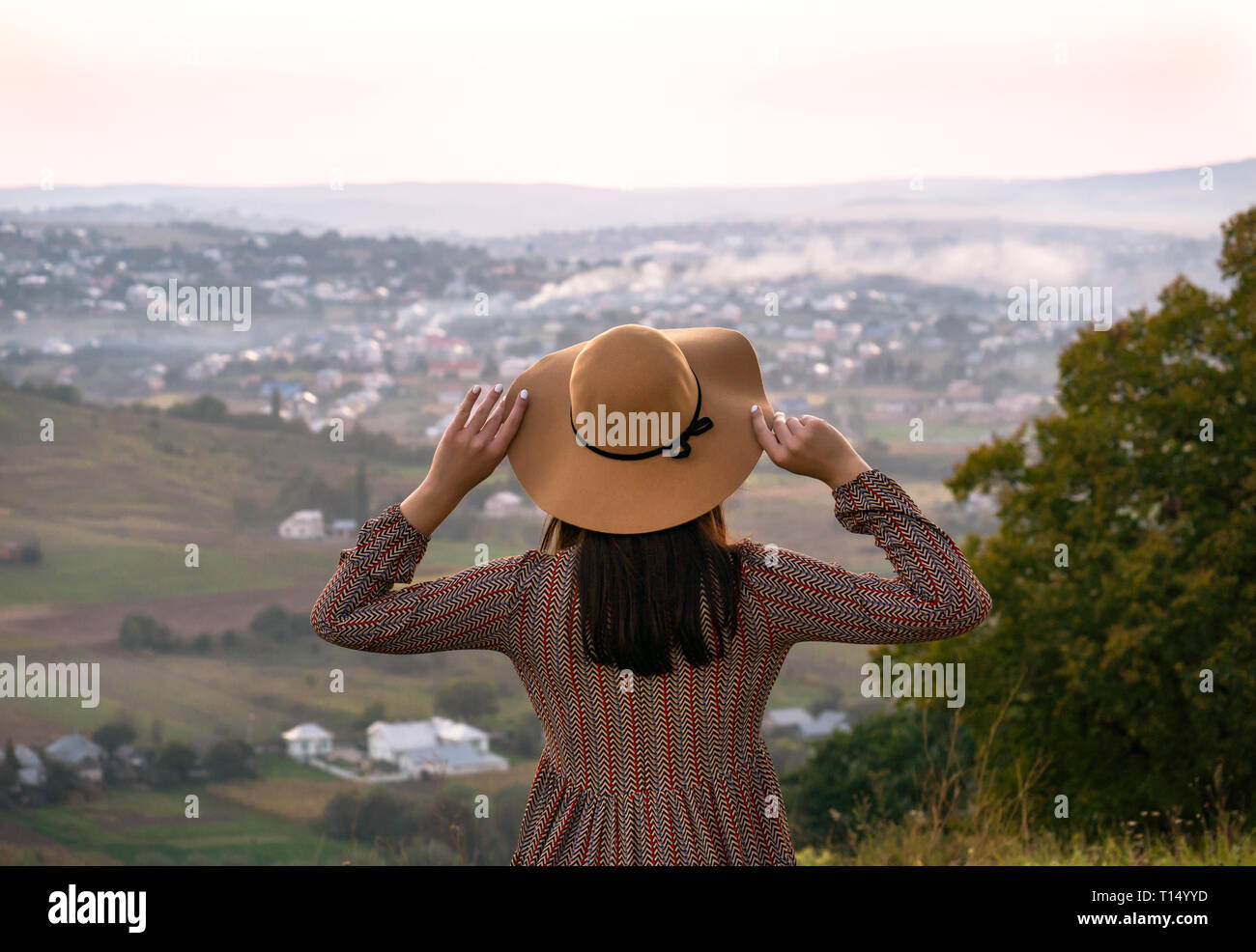 Schöne Mädchen in einen Hut schaut auf die Stadt bei Sonnenuntergang Stockfoto
