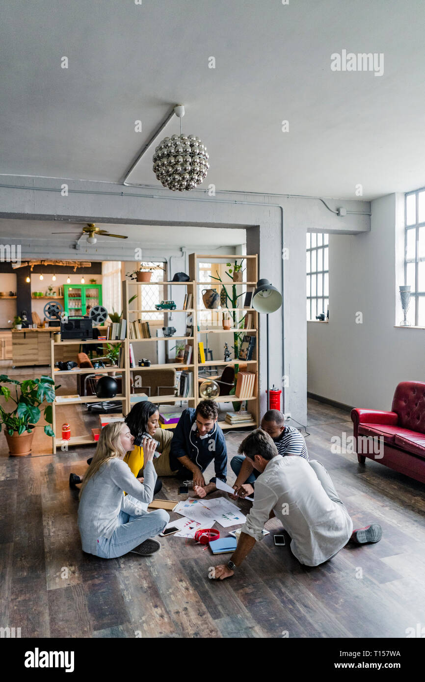 Business Team sitzen auf dem Boden diskutieren Dokumente in loft Büro Stockfoto