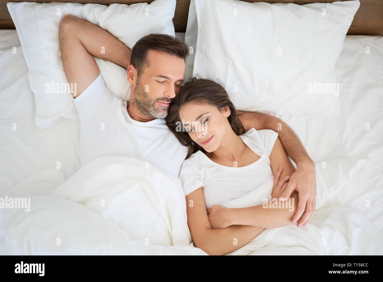 Paar im Bett liegen, schlafen mit Arme um Stockfoto