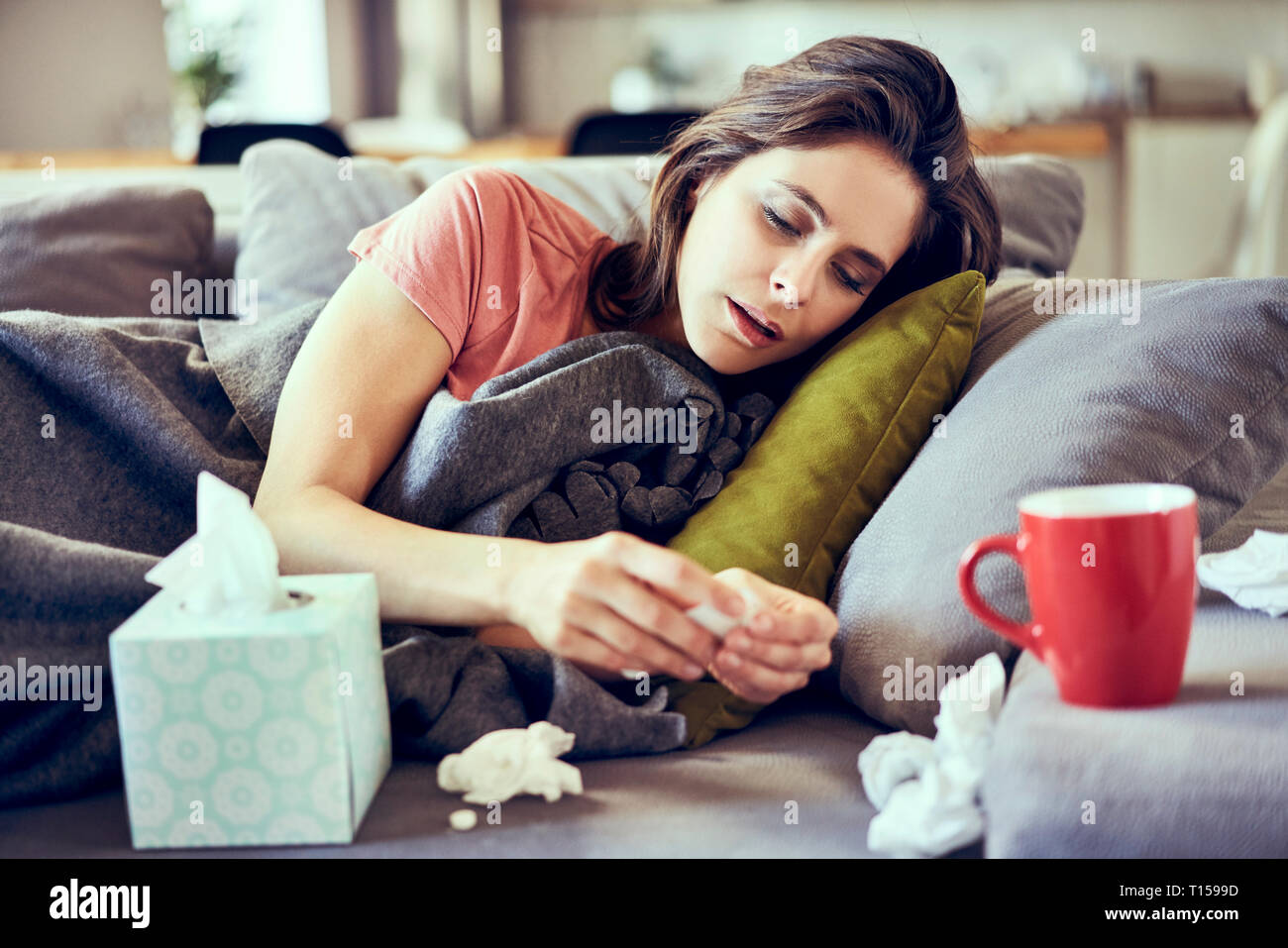 Porträt der kranke junge Frau liegt auf der überdachten in Decke versuchen Pillen für kalte zu nehmen Stockfoto