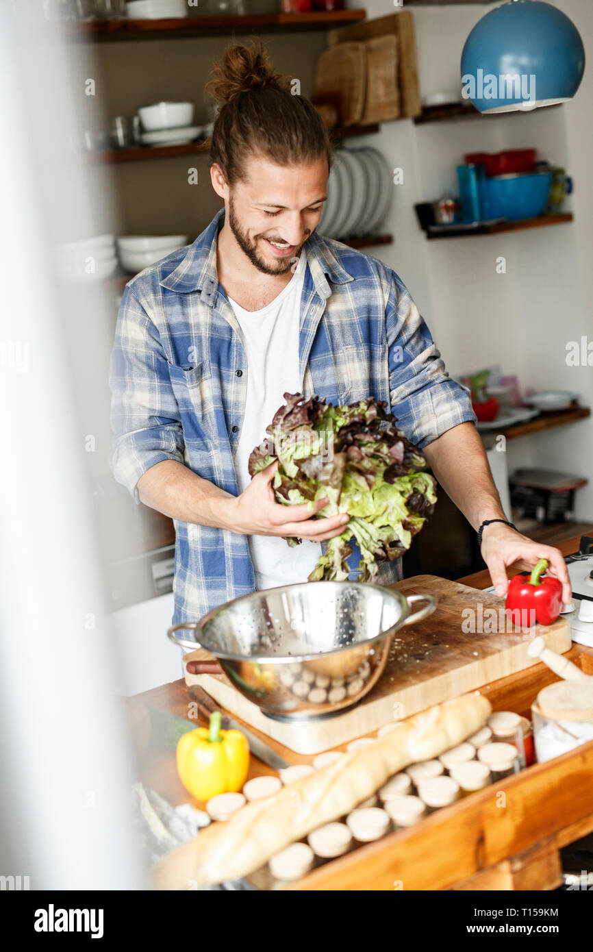 Junger Mann essen zu Hause Vorbereitung, Reinigung Salat Stockfoto