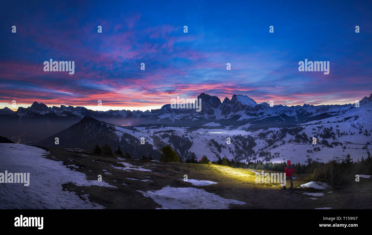 Einzelne Wanderer mit Scheinwerfer unter purple sky vor Sonnenaufgang in Bergdorf Seiser Alm, Italien Stockfoto