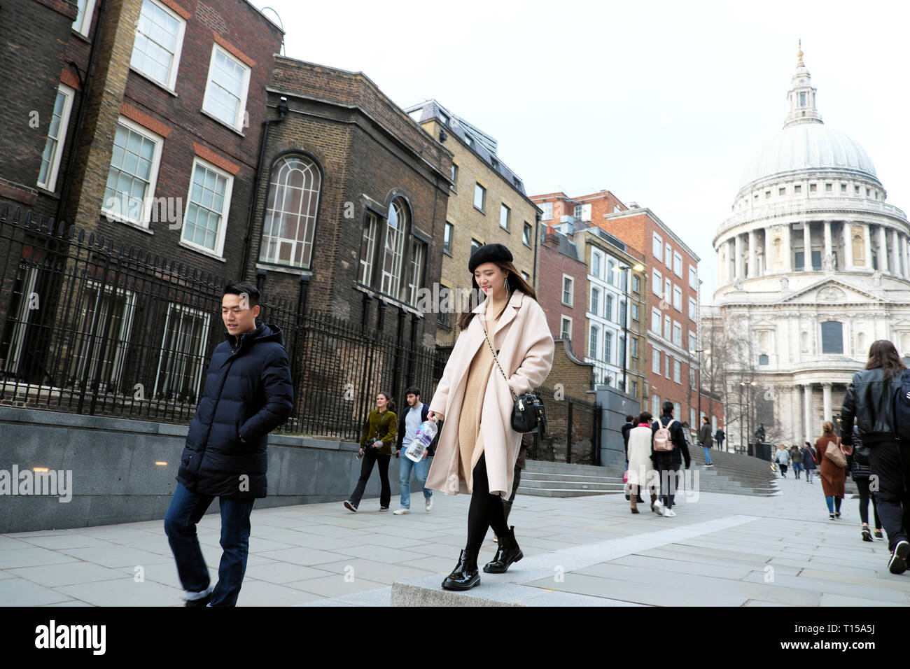 Ein stilvolles Chinesische Touristen paar Fuß in Richtung der Millennium Bridge außerhalb St Pauls Kathedrale in der Stadt London UK KATHY DEWITT Stockfoto