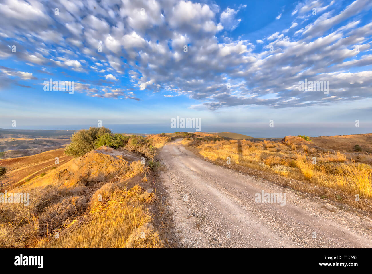 Rocky Road durch die hügelige Landschaft auf der Insel Zypern mit Blick auf das Meer im Hintergrund. Die heiße semi-ariden Klima hat die BSh correspondin Stockfoto