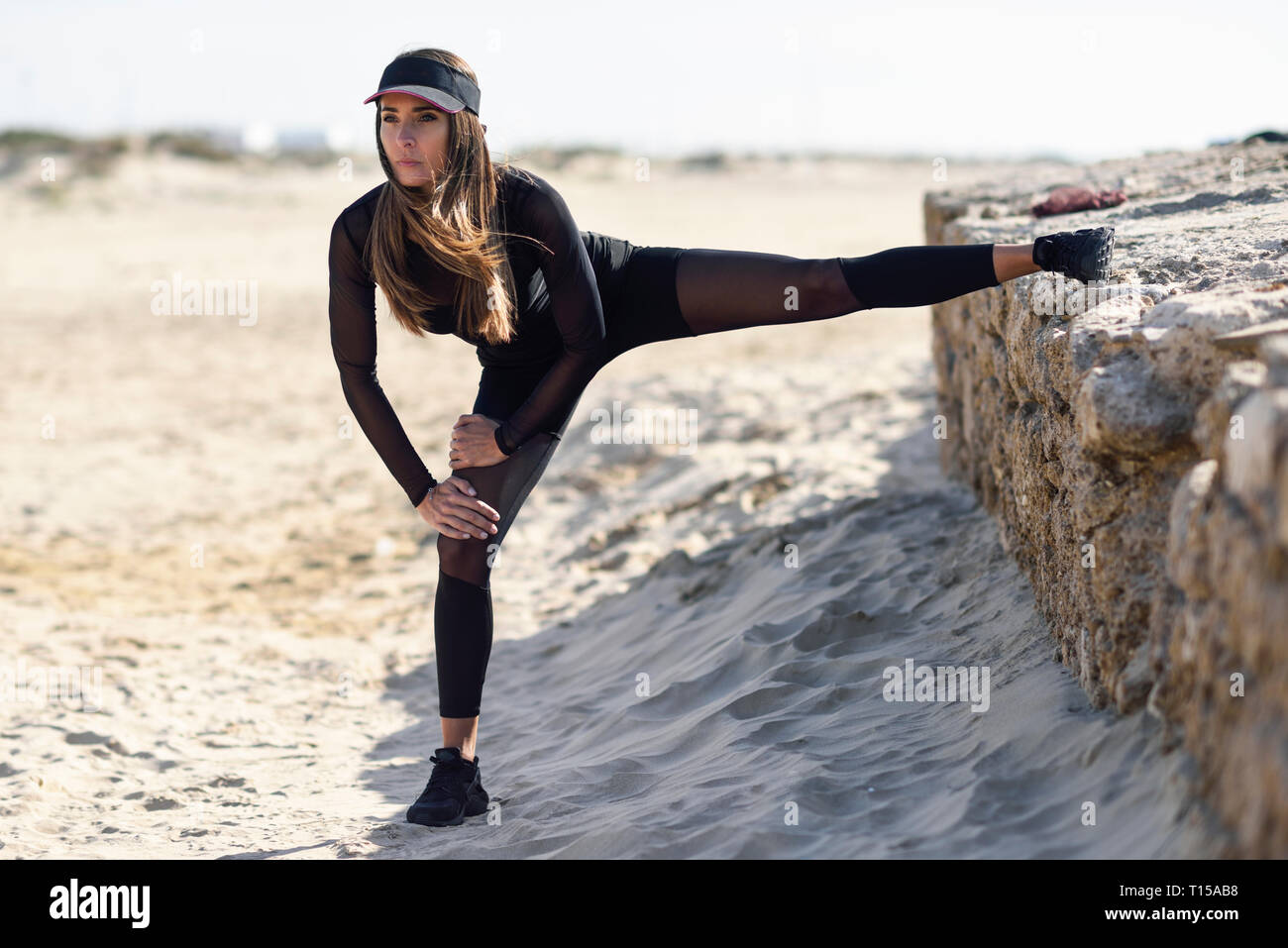 Sportliche Frau ihr Bein stretching auf stein Wand Stockfoto