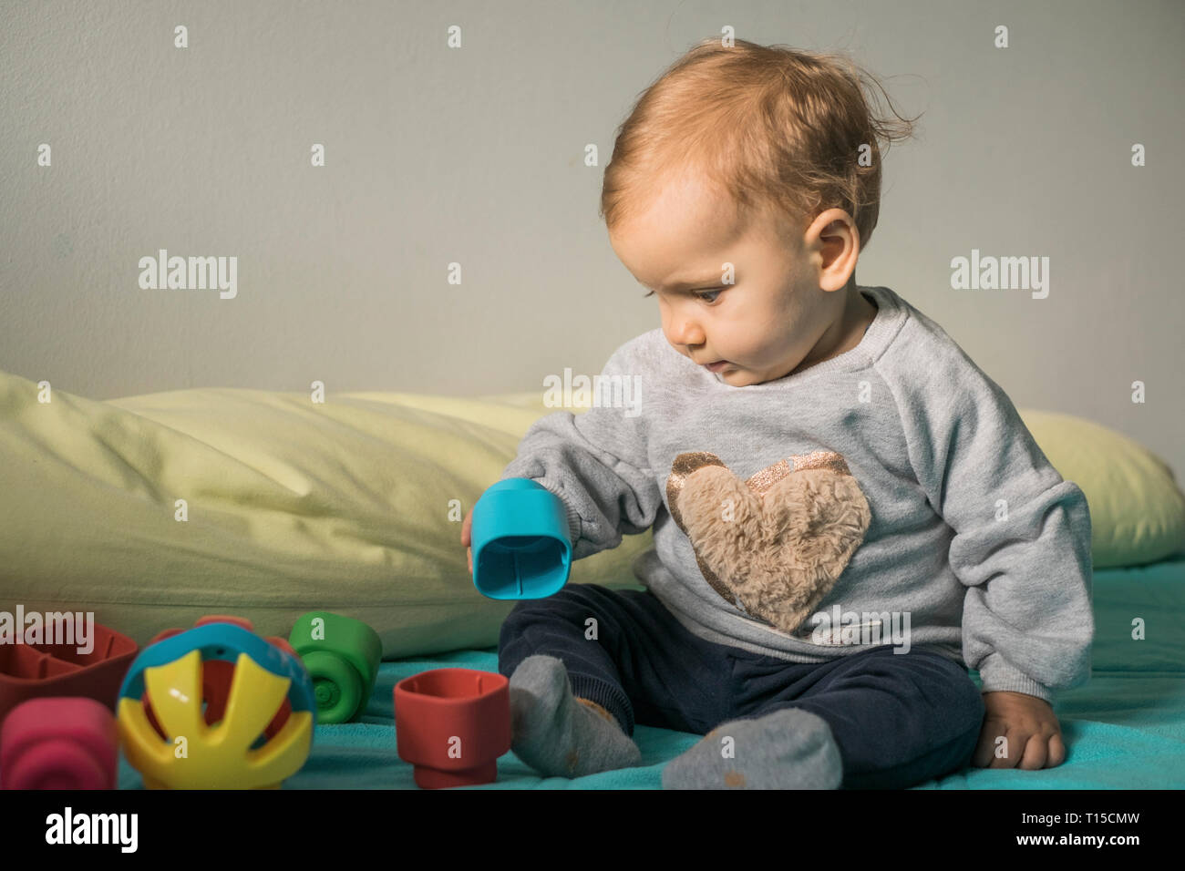 Baby Mädchen sitzen auf dem Bett spielen mit Spielzeug aus Kunststoff Stockfoto