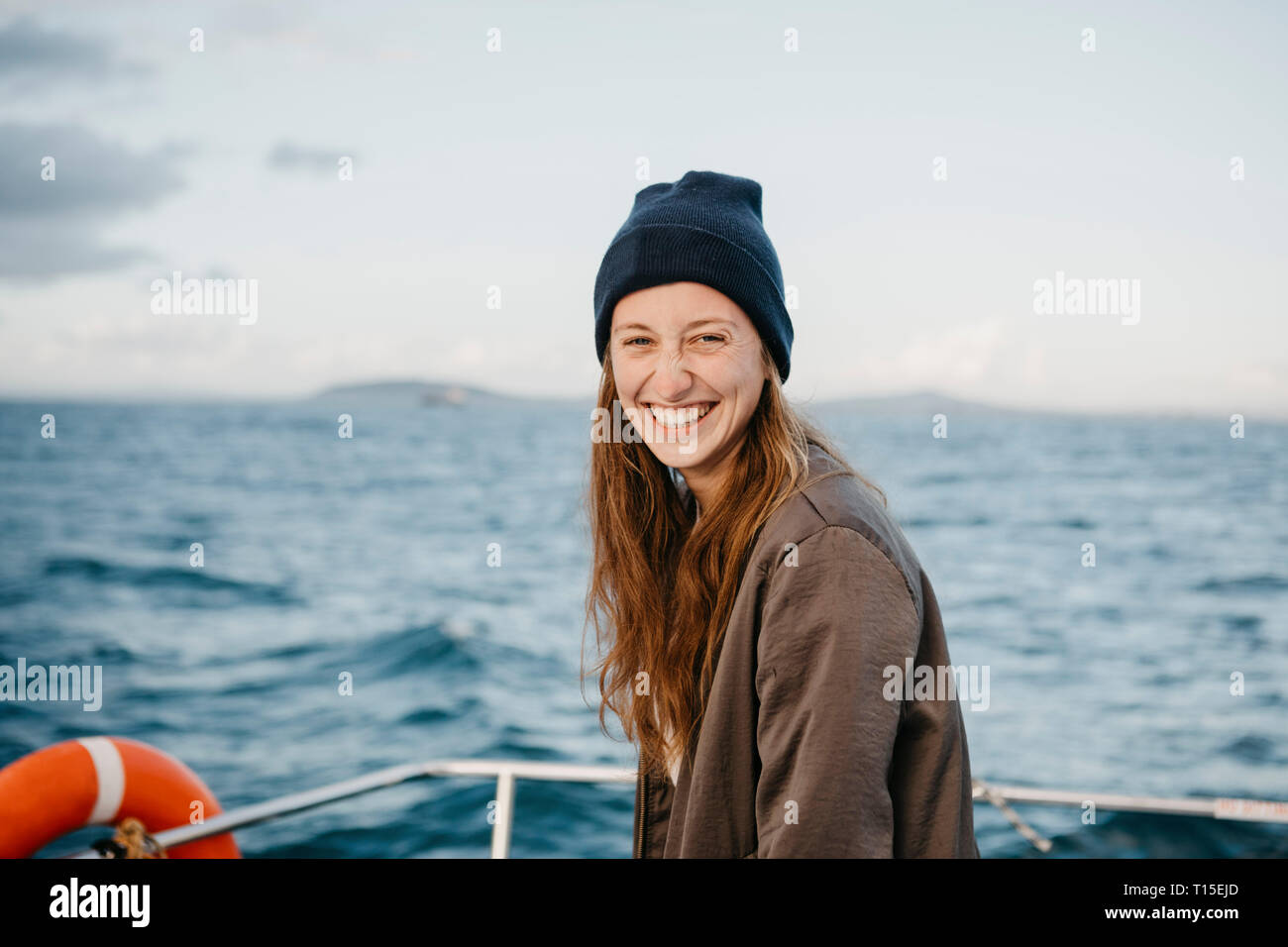 Südafrika, junge Frau mit Wollmütze lächelnd während der Bootsfahrt bei Sonnenuntergang Stockfoto