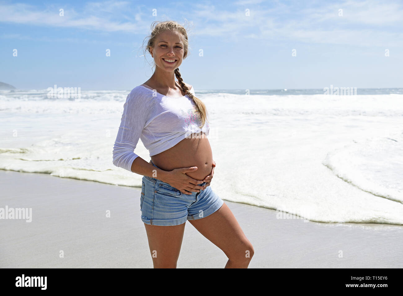 Portrait von lächelnden schwangere Frau am Strand Stockfoto