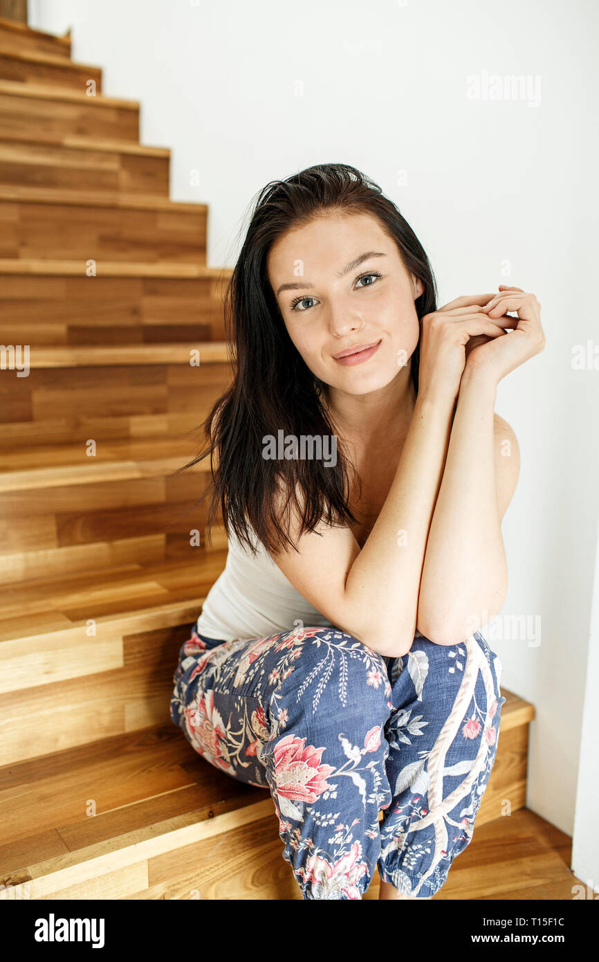 Hübsche Frau auf Treppe zu Hause sitzen, Porträt Stockfoto