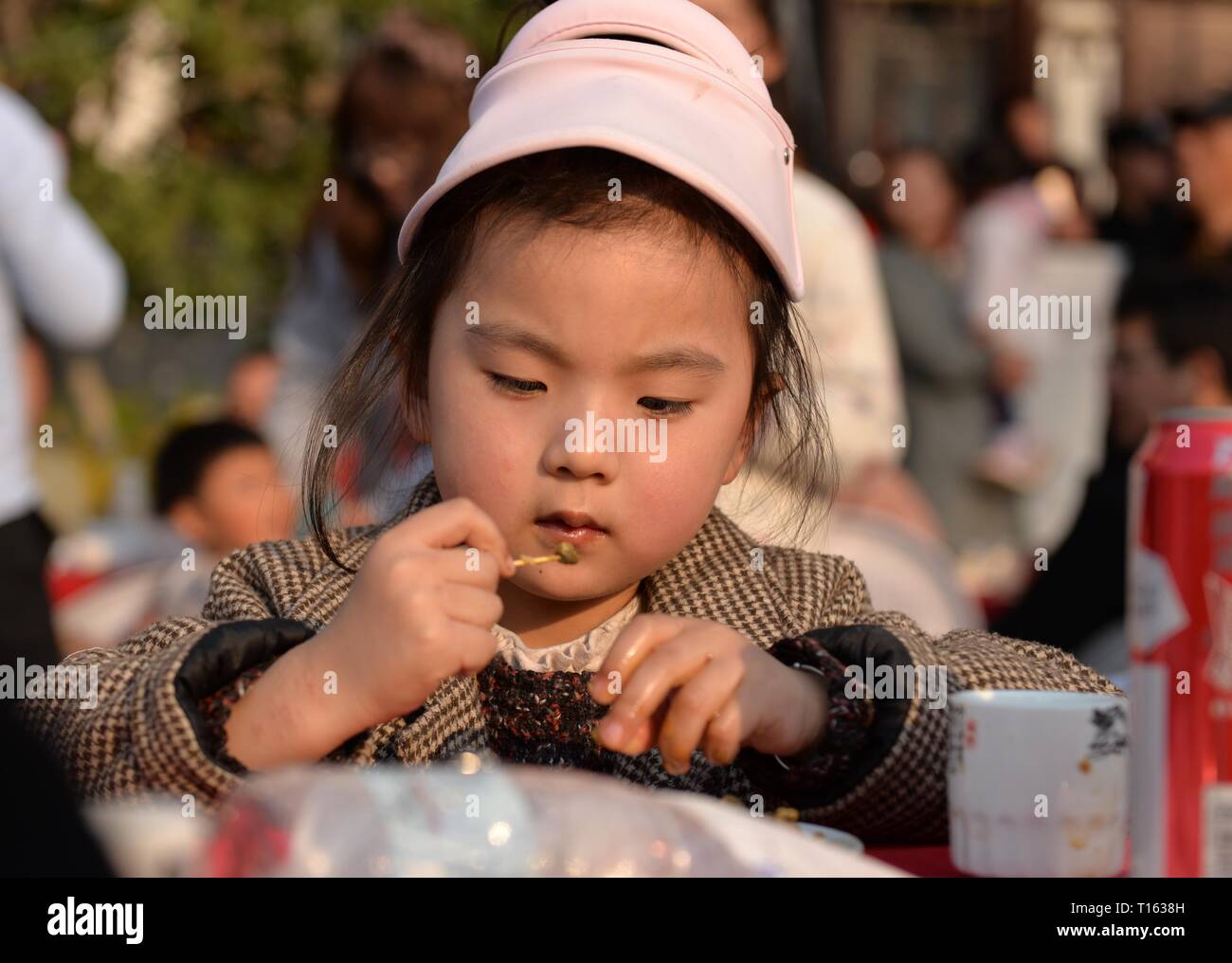 Ningbo, China. 23 Mär, 2019. Ein Mädchen Geschmack der Gerichte aus Luosi, eine Art Sumpfdeckelschnecke, während ein Festmahl in Jiangba Township von hongze Landkreis Huai'an City, East China, 23. März 2019 statt. Gerichte der Luosi sind in der Regel an der Straße Stände in China verkauft. Credit: Chen Liang/Xinhua/Alamy leben Nachrichten Stockfoto