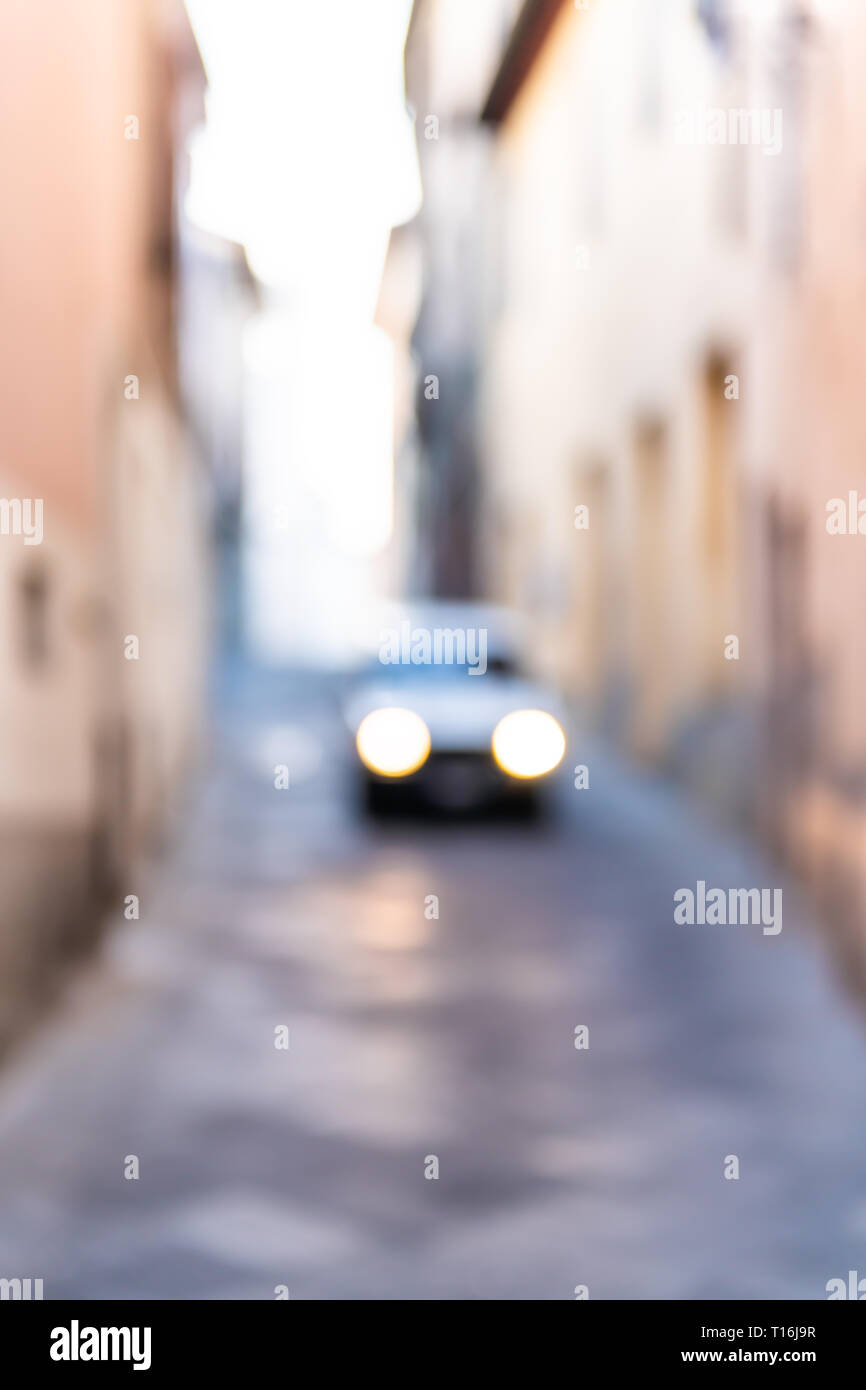 Chiusi, Italien Straße in der kleinen Stadt Dorf in der Toskana schmalen vertikalen Ansicht mit orange rosa gelbe Wände und Auto Scheinwerfer abstrakte bokeh Blu Stockfoto