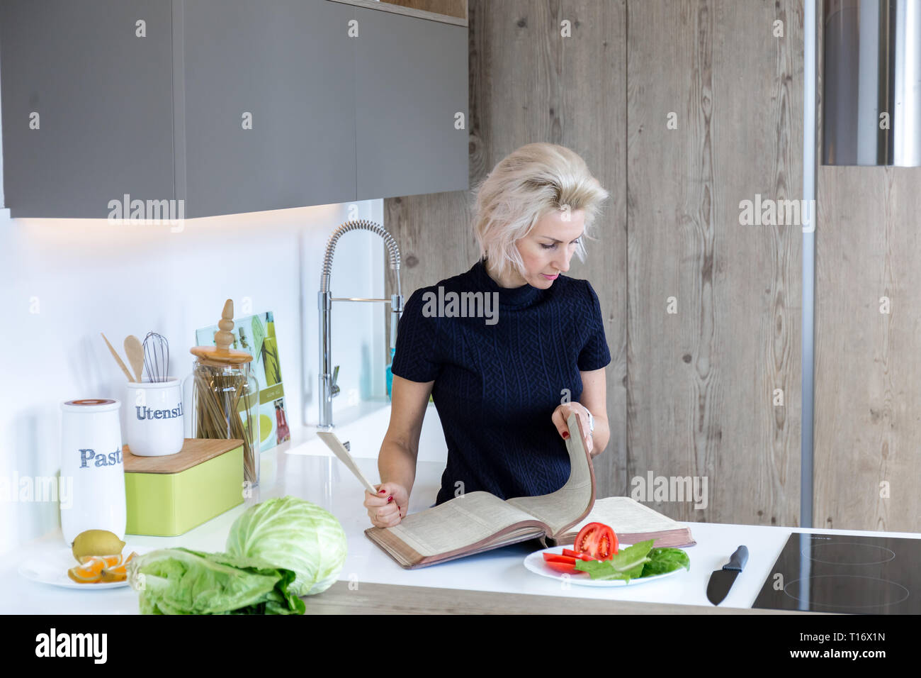 Junge blonde Frau, kochen in der modernen Küche Stockfoto