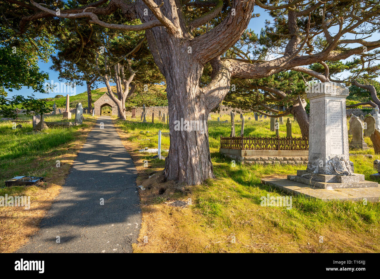 Weg durch den Friedhof mit krummen Grab Steine des St. Tudno Kirche, Llandudno, Wales, Vereinigtes Königreich unterbrochen Schattiert Stockfoto