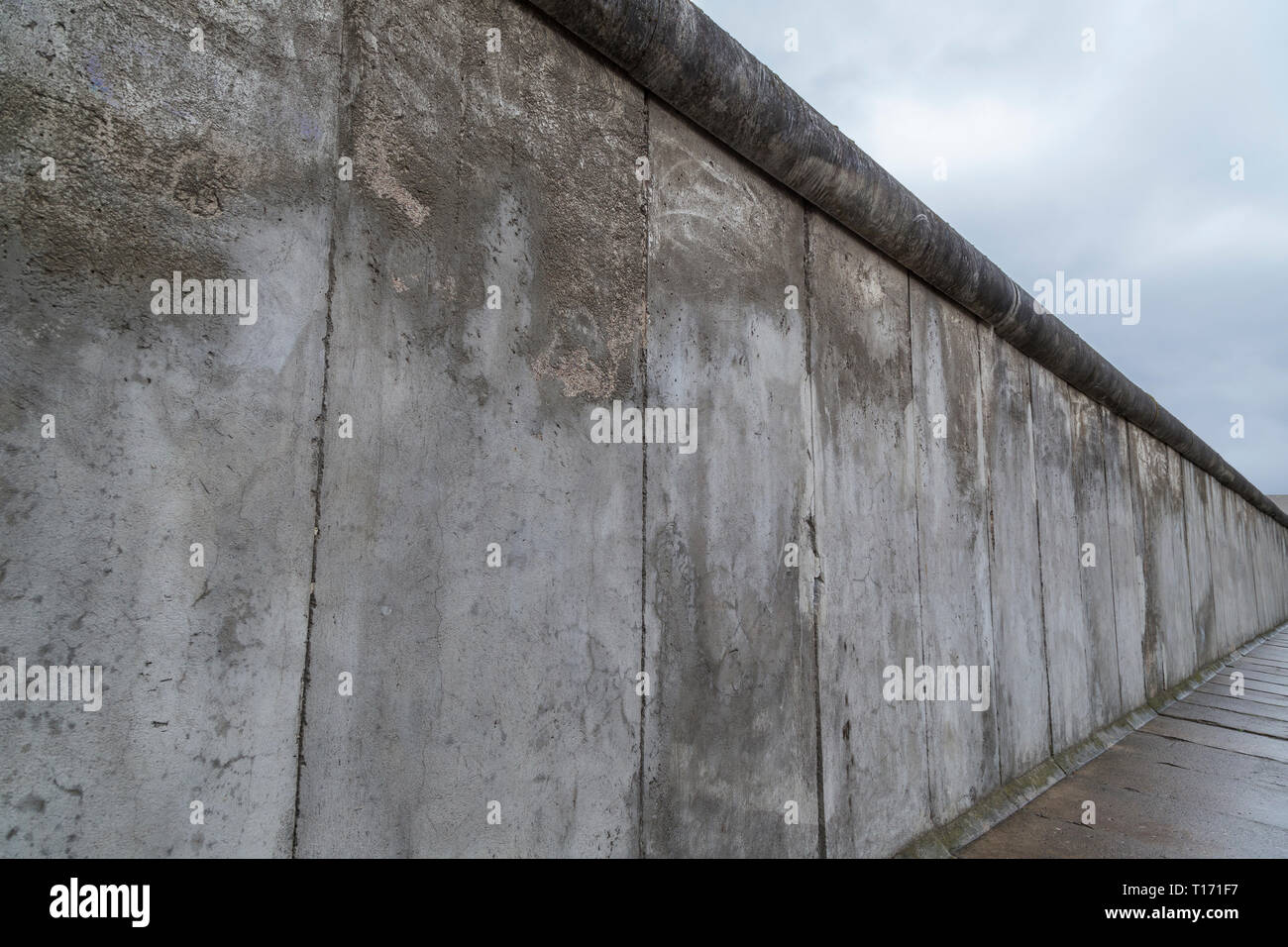 Seitliche Sicht auf einen Abschnitt der Berliner Mauer an der Gedenkstätte Berliner Mauer (Berliner Mauer) in Berlin, Deutschland, an einem bewölkten Tag. Stockfoto