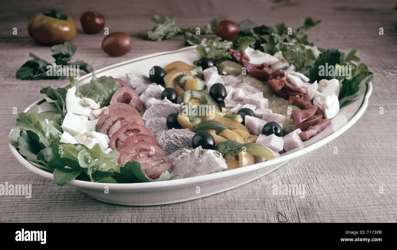 Ein beliebtes Gericht der amerikanischen Küche - Cobb Salat, bestehend aus grünen, Eier, Tomaten, Käse, Fleischwaren, in Reihen gestapelt auf eine große Schüssel und poure Stockfoto