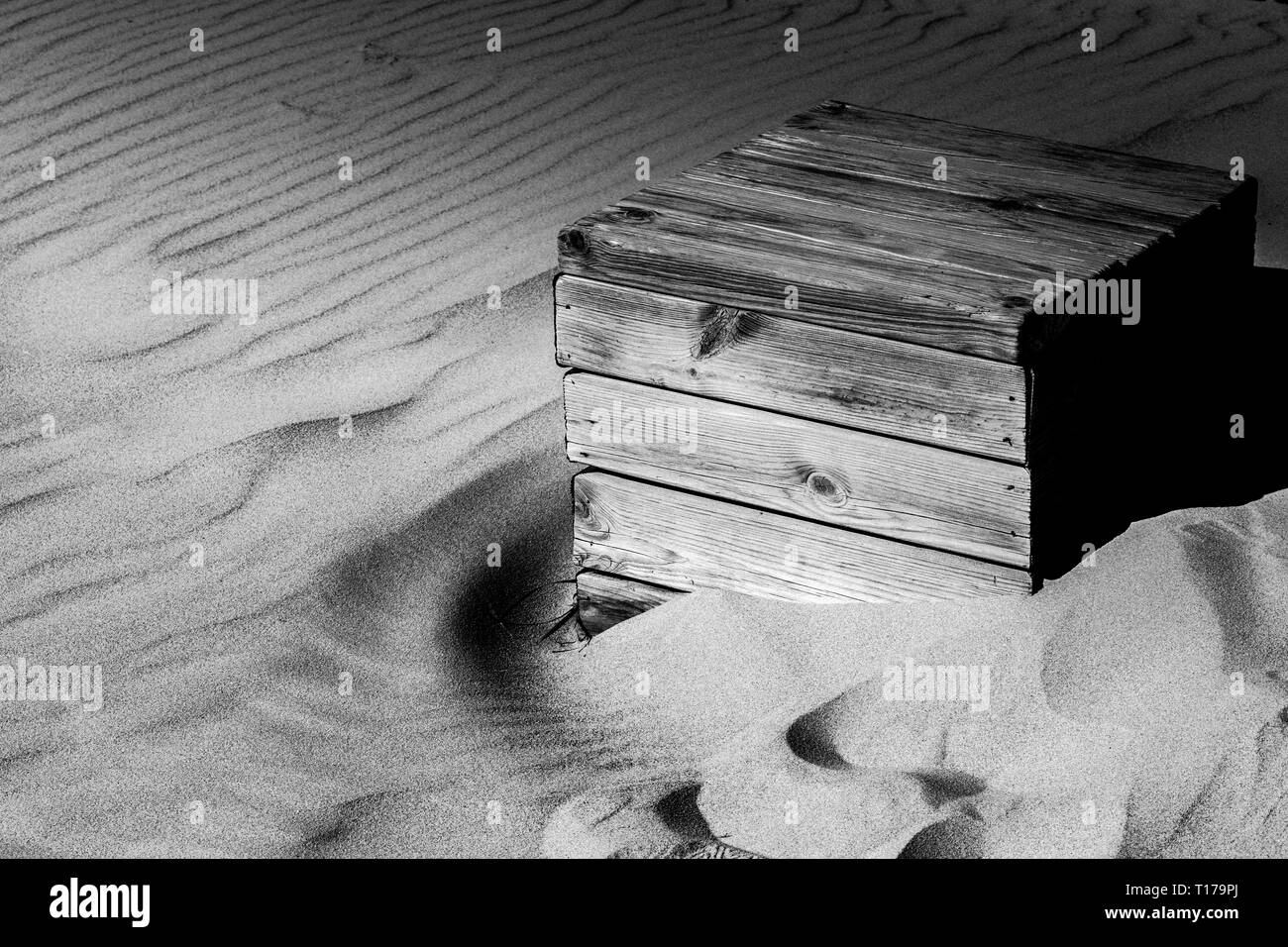 Ein verwittertes Holz- box langsam durch Sand am Strand von Bolonia, Spanien verbraucht in Schwarz und Weiß Stockfoto