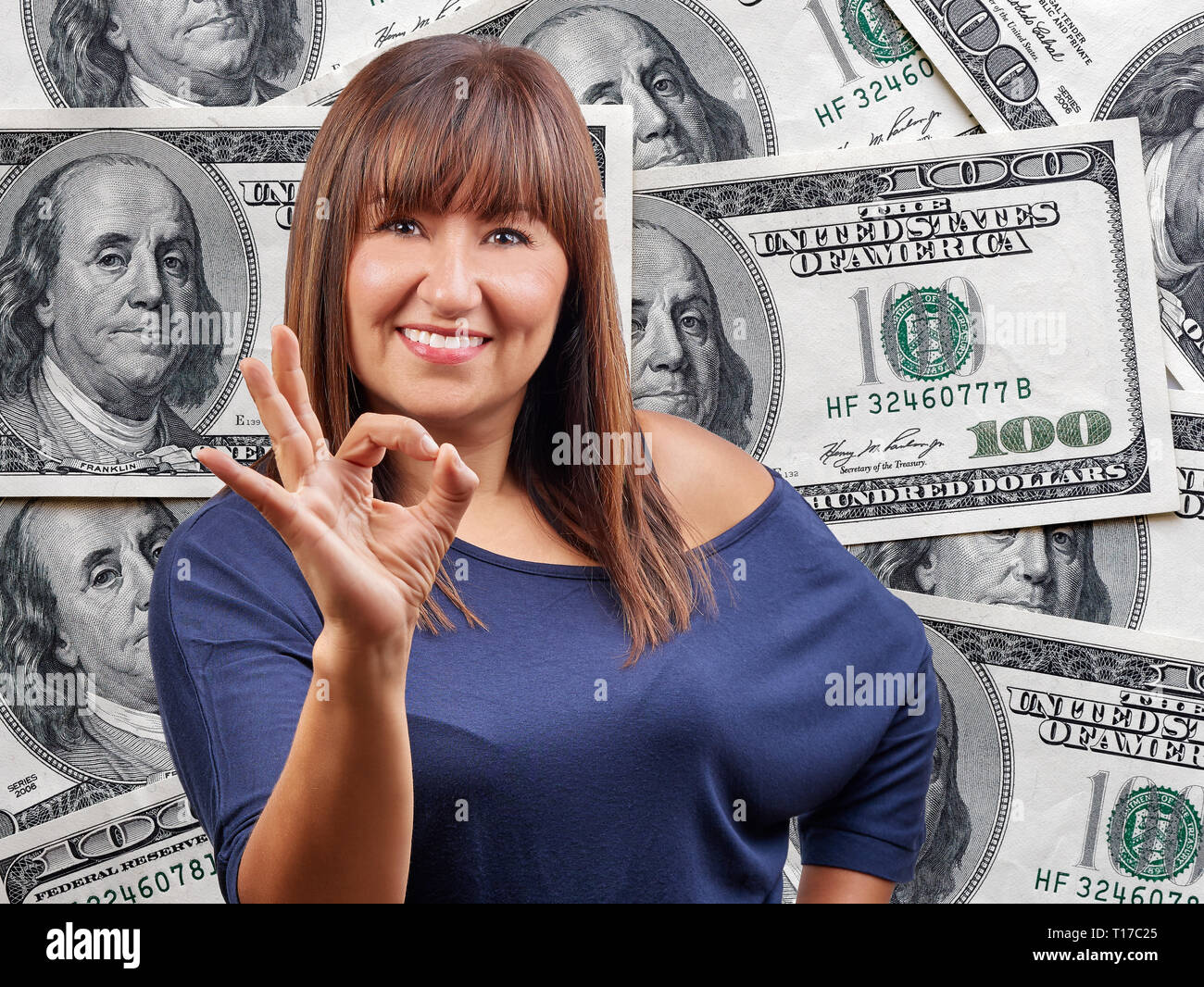 Gerne schöne Frau ok Zeichen Geste gegen hundert Dollar Bills heap Hintergrund Stockfoto