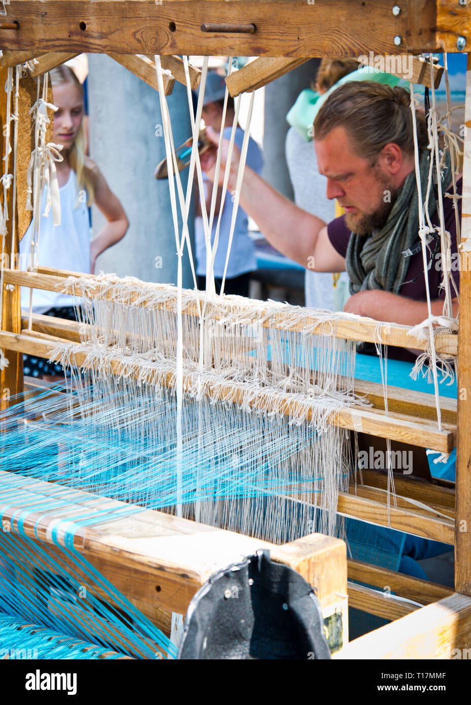Mann Betrieb altmodischen Holz Handwebstuhl Herstellung handgefertigten Schals für Touristen. Junge Mädchen steht beobachten diese geschickte Weberei Künstler bei der Arbeit. Stockfoto