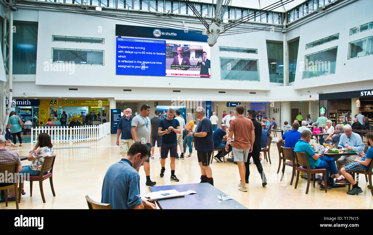 Passagiere, die zum Abflugbrett aufschauen, stehen, sitzen, warten auf Informationen über verspätete Züge am Eurotunnel-Terminal England, Großbritannien. Stockfoto