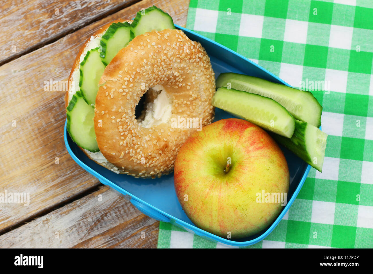 Gesundes Lunchpaket, bestehend aus Bagel mit Frischkäse, Gurken und Apple Stockfoto