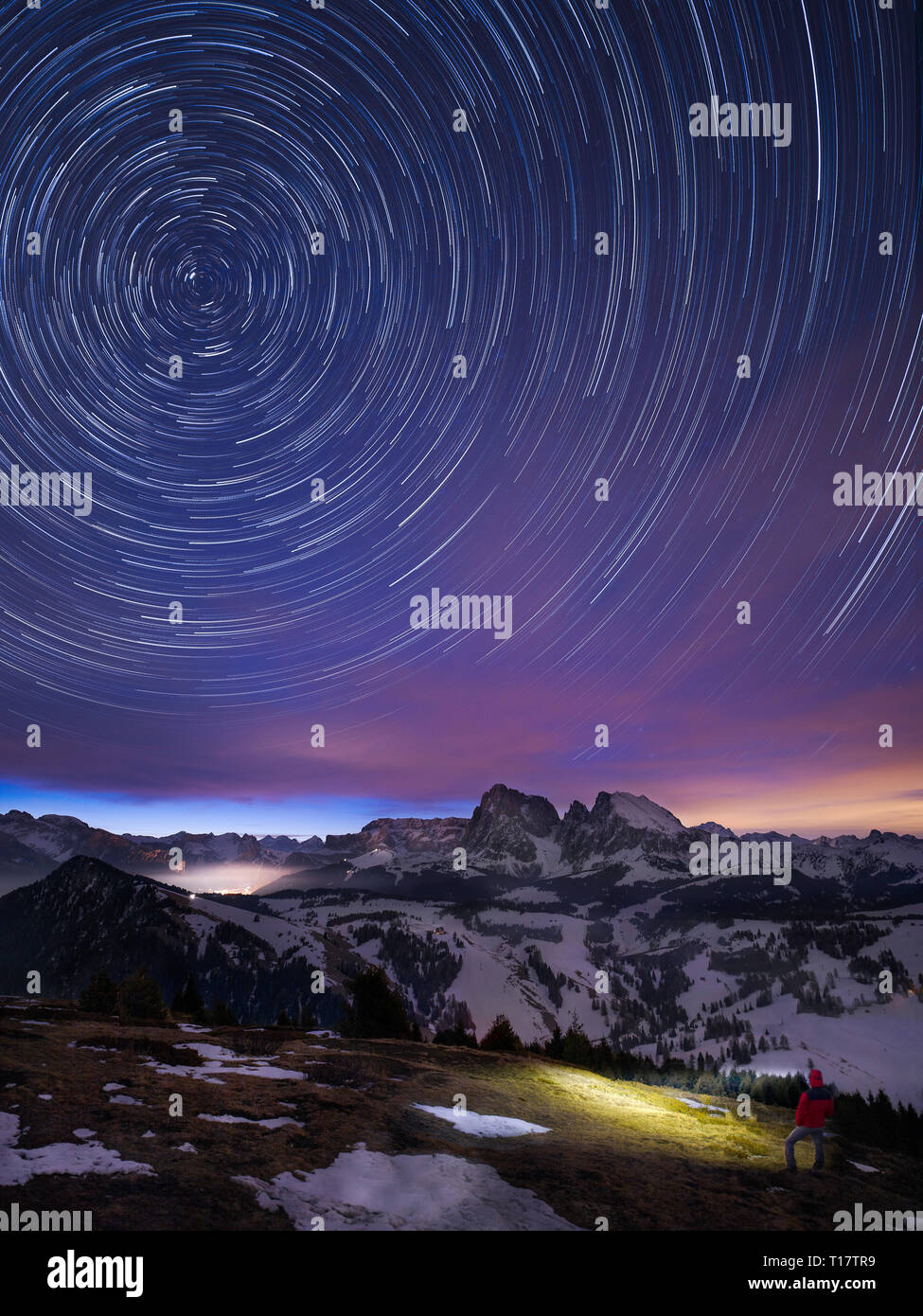 Einzelne Wanderer mit Scheinwerfer unter Sternenhimmel vor Sonnenaufgang in Bergdorf Seiser Alm, Italien Stockfoto