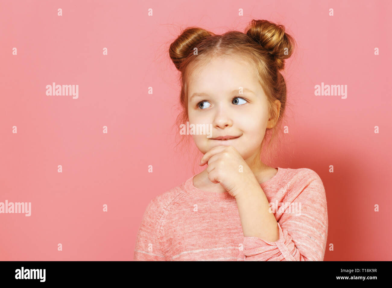 Close-up Portrait von Nizza schöne attraktive faszinierende winsome Kind Mädchen mit Brötchen, nachdenklich bis zur Seite über rosa Hintergrund Stockfoto