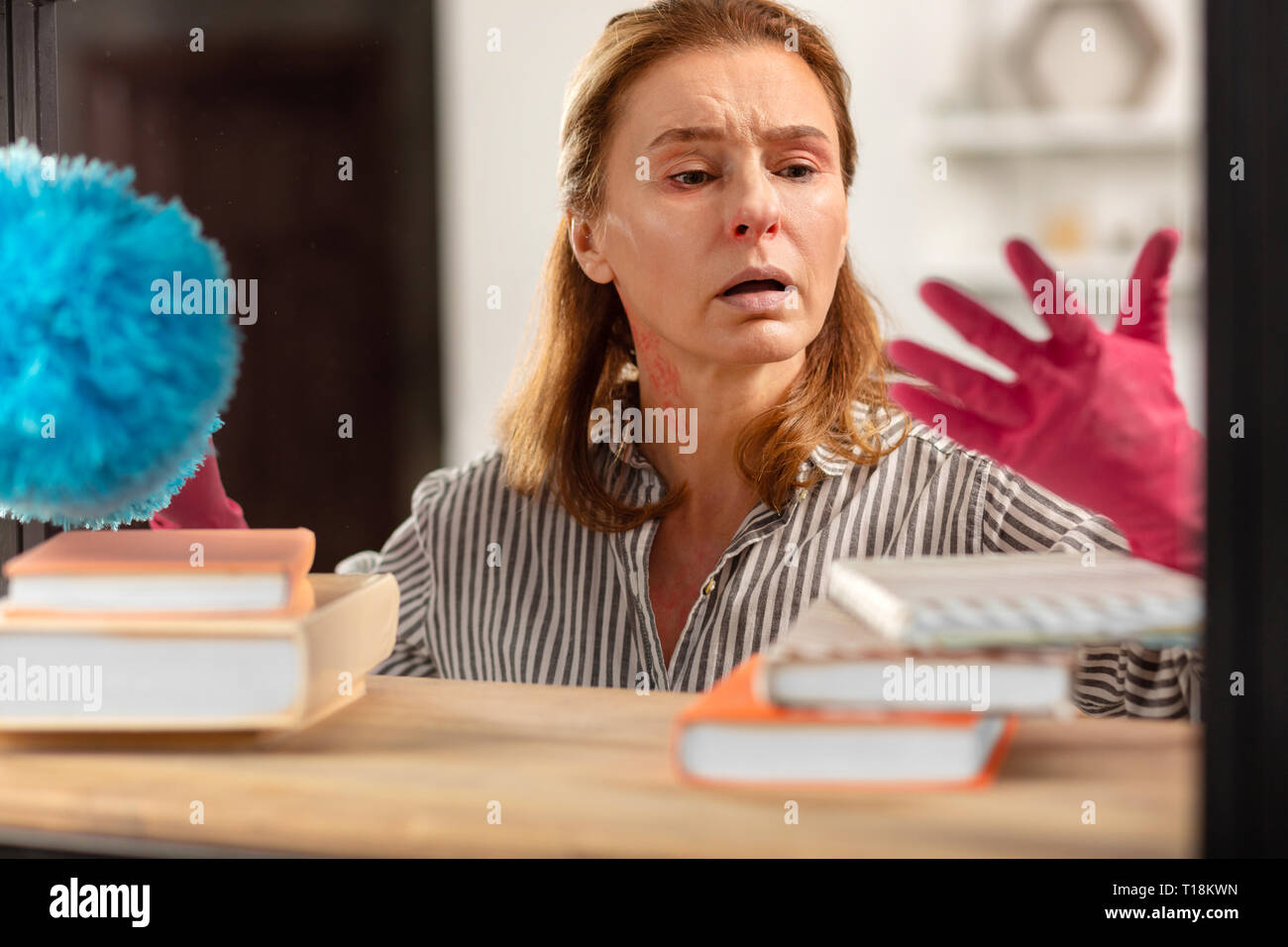 Dark-eyed Hausfrau tragen rosa Handschuhe Müdigkeit von Staub Stockfoto