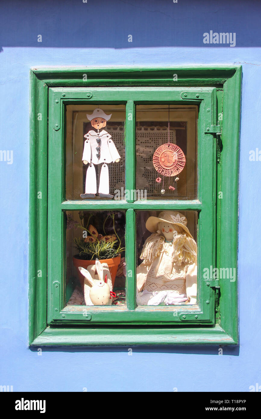 Vintage Spielzeug in grün Fenster auf der blauen Wand Hausfassade gerade Stockfoto