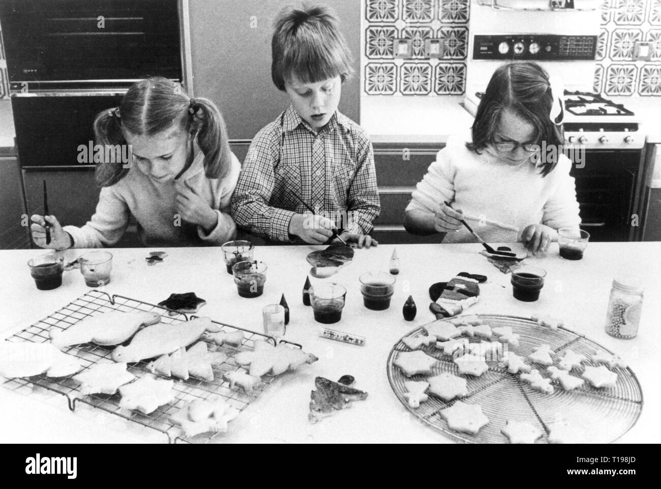 Haushalt, Kochen und Backen, drei Kinder malen Weihnachten Kekse, 1970er Jahre, Additional-Rights - Clearance-Info - Not-Available Stockfoto