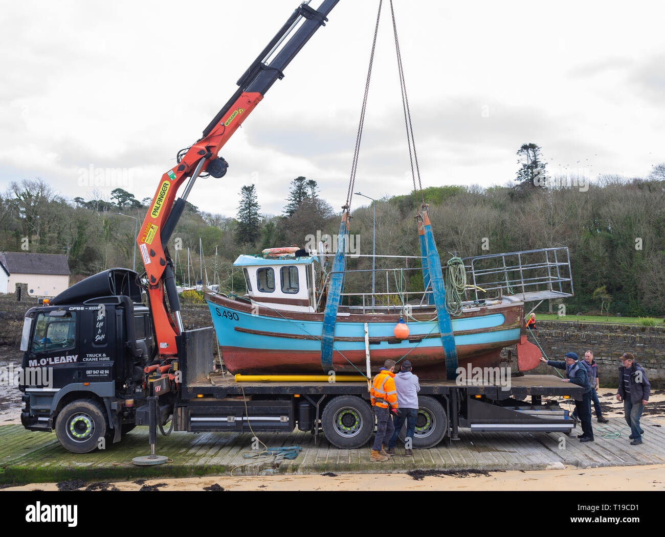 Kran ein Fischerboot auf einem Tieflader Lkw von fünf Männern geholfen. Stockfoto