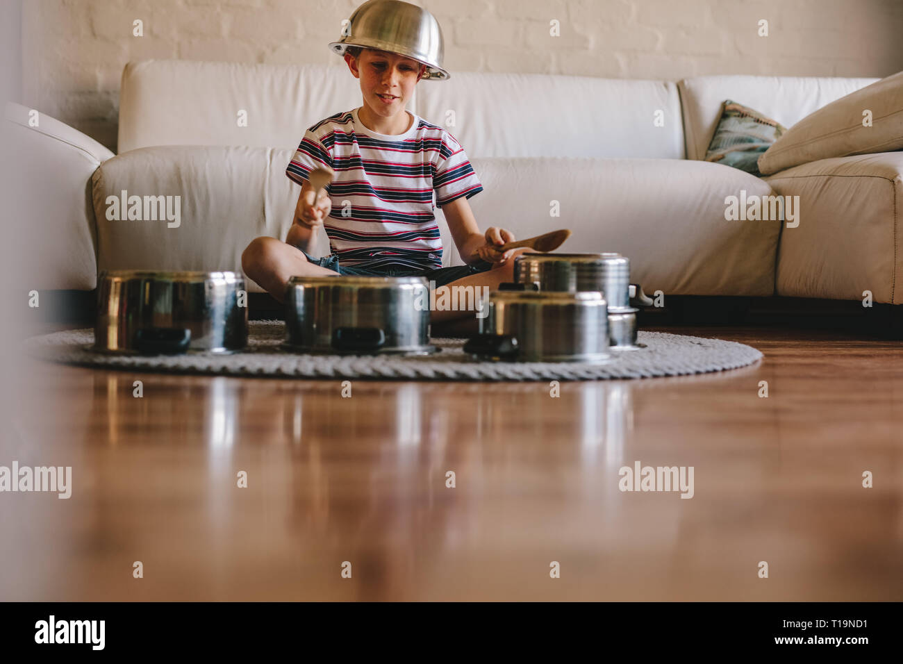 Wenig Musiker Schlagzeug spielen auf Küchenutensilien zu Hause. Unschuldige junge vorzugeben, ein Drummer sitzt auf dem Boden und Spielen auf Utensilien Stockfoto