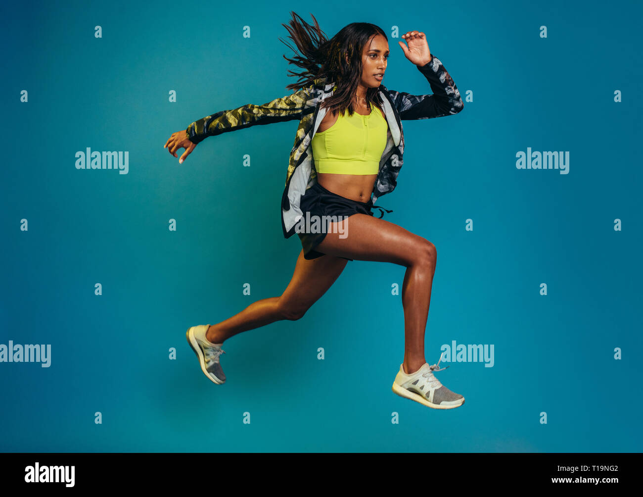 Volle Länge geschossen von Fitness Frau über blauen Hintergrund. Hispanic weibliche Modell tun, ausüben. Stockfoto