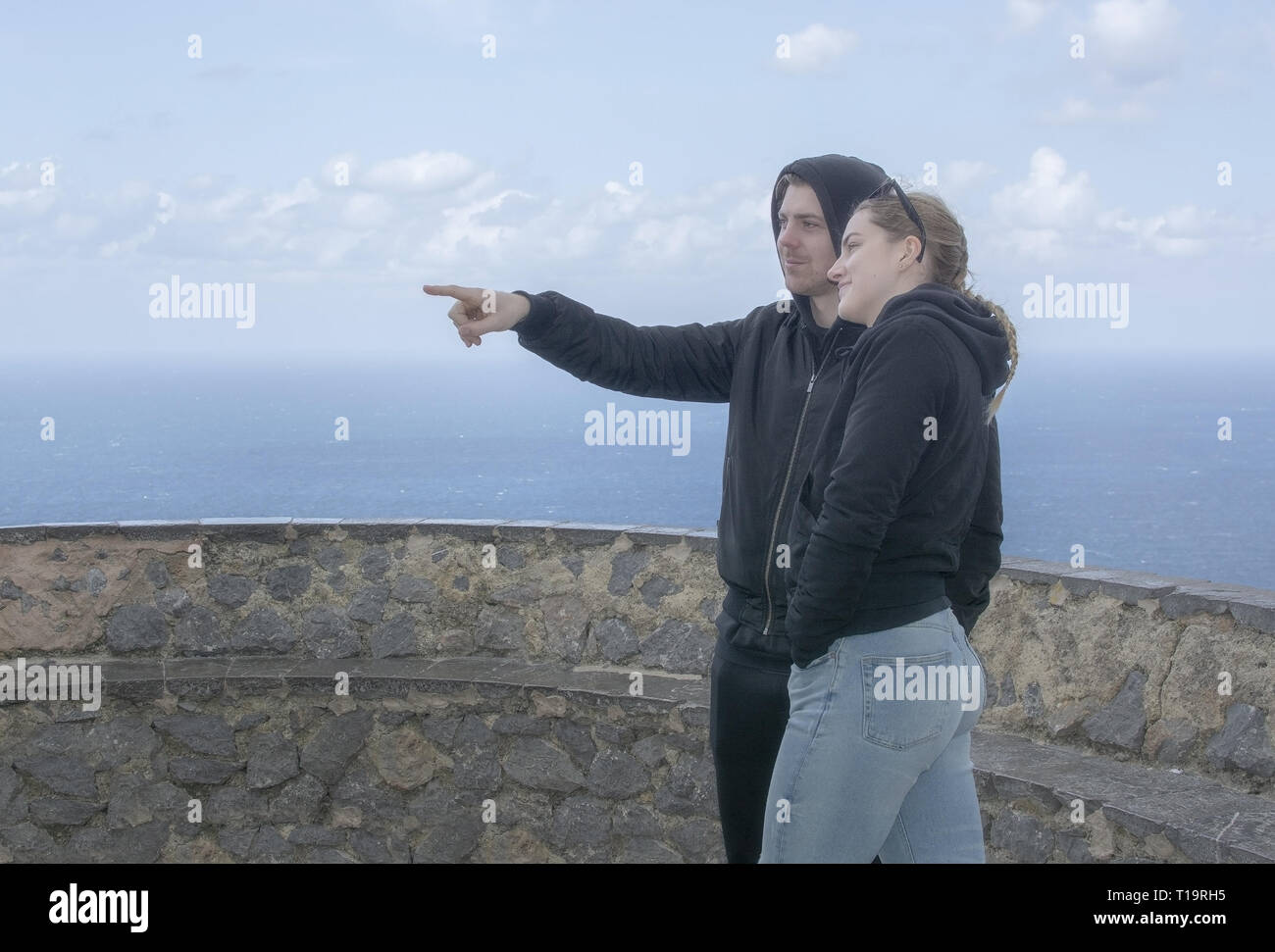 Junge schöne beiläufig Paar stand hoch oben zeigen und beobachten Sie das Meer an einem Frühlingstag in Mallorca, Spanien, gekleidet. Stockfoto