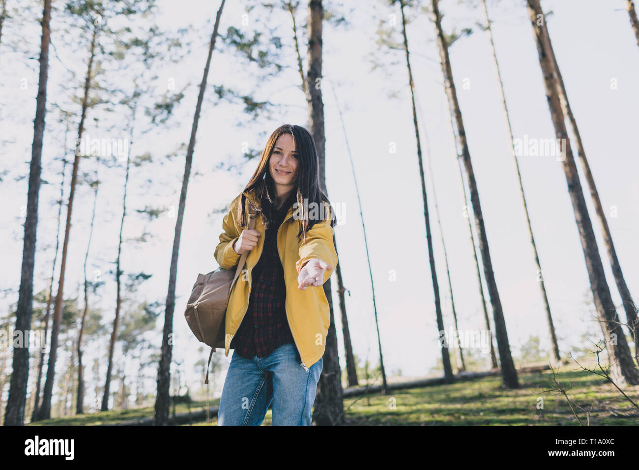 Junge Frau in das Holz mit einem Rucksack gibt eine Hand schauen direkt in die Kamera Stockfoto