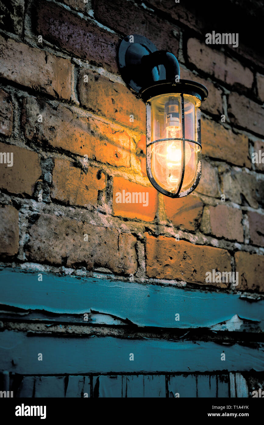 Eine einzige alte Glas und Metall outdoor Licht auf die Wand in einer Gasse Stockfoto