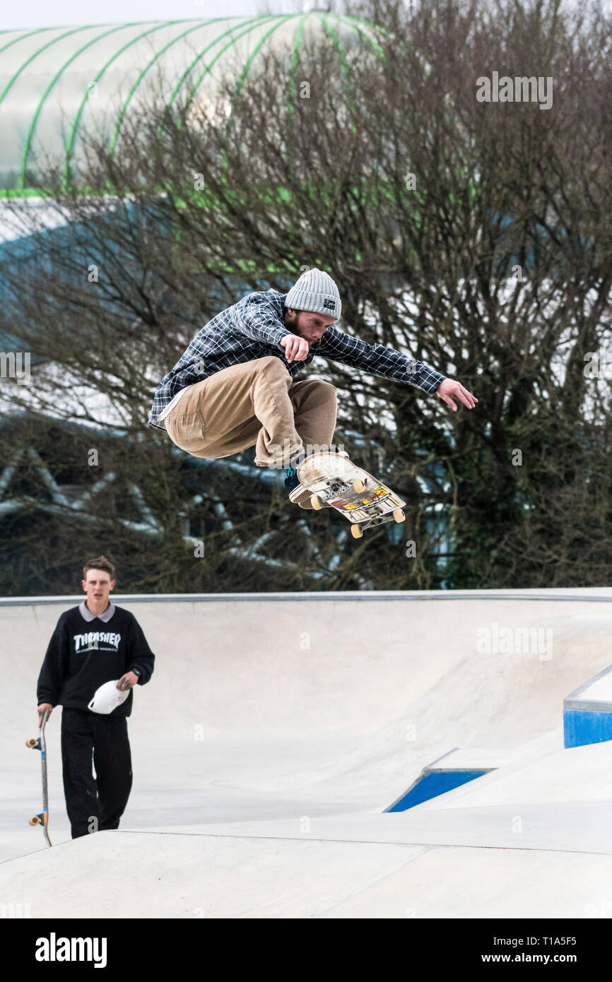 Ein Skateboarder Durchführen einer Antenne Trick an konkreten Wellen Skateboard Park in Newqay in Cornwall. Stockfoto